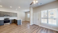 This well-appointed two-story home offers generous living space across two floors, accommodating five bedrooms and four full bathrooms. The main level features an open-concept kitchen and living area with warm hardwood-style flooring that flows throughout. The kitchen is outfitted with grey shaker-style cabinetry, a classic subway tile backsplash, marble-look countertops with a peninsula, stainless steel appliances, and recessed lighting — making it an ideal hub for daily living and entertaining. The living area is bright and welcoming, with ceiling fans and multiple windows that invite natural light. An attached garage with an automatic opener provides convenient interior access. Upstairs, the upper floor houses the majority of the bedrooms, including a spacious primary suite complete with a well-appointed ensuite bathroom featuring a dual-sink vanity with marble-look countertops, and a walk-in closet with built-in shelving. The additional bedrooms are comfortably sized, each with hardwood-style flooring, ceiling fans, and natural light from windows. Four closets throughout the home provide ample storage. The neutral color palette, clean lines, and consistent finishes give the entire home a cohesive, modern aesthetic.