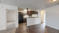 This single-story home offers a practical and comfortable layout across 3 bedrooms, 3 bathrooms, and 2 closets. The open-concept living and kitchen area serves as the heart of the home, where rich dark hardwood-style flooring contrasts with crisp white walls and a textured ceiling. The kitchen is well-equipped with dark espresso-toned cabinetry, dark countertops, black appliances including a full-size refrigerator, a double stainless steel sink, and a built-in overhead range hood. A peninsula counter provides additional workspace and creates a natural divide between the kitchen and living area. The spacious living room features plush neutral carpeting, a classic black-framed fireplace, and a sliding glass door that allows natural light to pour in. Each of the three bedrooms is carpeted and includes a ceiling fan with light fixture and a window with blinds, providing natural light and ventilation. The primary bedroom offers a generous footprint with ample room for furnishings. The three bathrooms are consistently finished with dark wood-tone vanities, stone-look countertops, single-basin sinks, and tiled shower-tub combinations, complemented by wood-style flooring. Two closets provide dedicated storage throughout the home.