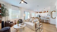 Located in Surprise, AZ, this well-appointed single-story home offers three bedrooms and three bathrooms within a thoughtfully designed open-concept floor plan. Light wood-look flooring flows throughout, lending warmth and continuity to every room.

The living area is bright and airy, anchored by a ceiling fan, generous natural light from multiple windows, and sliding glass door access. It connects seamlessly to a stylish kitchen featuring white shaker cabinetry, a large center island with bar seating, pendant lighting, stainless steel appliances, and ample counter space — ideal for both everyday living and entertaining.

A dedicated sitting area off the main living space offers a cozy retreat, complete with a wall of open wood shelving and natural light from a large window. Hallways connect the home's bedrooms efficiently, with a walk-in closet providing organized storage in the primary suite. The primary bedroom is a comfortable, well-sized retreat with vaulted ceiling accents and a sliding closet. Additional bedrooms are equally well-lit with ceiling fans and window views. A dedicated laundry area with side-by-side washer and dryer adds practical convenience. Three full bathrooms serve the household comfortably throughout.