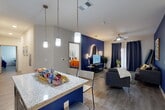 Located at 2523 Avenue M in Huntsville, Texas, this well-appointed single-story residence offers four bedrooms and four bathrooms within a thoughtfully designed floor plan. The open-concept living, dining, and kitchen area serves as the heart of the home, highlighted by a striking bold blue accent wall adorned with decorative lighting and artwork. The living room features wood-look flooring, a ceiling fan, and ample natural light filtered through navy grommet curtains. The kitchen is outfitted with dark cabinetry, granite-look countertops, a white subway tile backsplash, stainless steel appliances including a range and over-the-range microwave, and a peninsula with pendant lighting and bar seating — ideal for casual dining and entertaining. Each of the four bedrooms is generously sized, offering ceiling fans and closet space, with dedicated workspaces visible in select rooms. Each bedroom is paired with its own private bathroom, featuring granite-topped vanities, dark cabinetry, wood-look flooring, and tub/shower combinations with tile surrounds. A dedicated laundry room and hallway connecting all spaces add to the home's functional layout, making it an efficient and stylish living option.