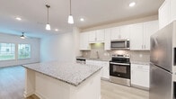 Located at 12525 Tibbets Lane in Jacksonville, FL, this well-appointed one-bedroom, one-bathroom unit offers a thoughtfully designed single-floor layout. The open-concept living area seamlessly combines the kitchen, dining, and living spaces, creating a bright and functional hub for daily living. The kitchen is a standout feature, showcasing crisp white shaker cabinetry, granite countertops, a large center island with pendant lighting, a tile backsplash, and a full suite of stainless steel appliances including a refrigerator, range, microwave, and dishwasher. Light hardwood-style flooring flows throughout the main living areas, complemented by recessed lighting and a ceiling fan. The bedroom offers plush carpeting, dual windows that invite natural light and outdoor views, a ceiling fan, and access to a dedicated closet. The bathroom features a granite-topped vanity with white cabinetry, a tiled tub/shower combination, and grab bars for added accessibility. Additional conveniences include an in-unit laundry area and an entry hallway. Neutral tones and clean finishes throughout give the space a modern, move-in-ready feel.