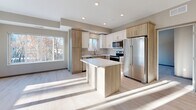 Located in Alexandria, MN, this single-floor, 4-bedroom, 2-bathroom home offers a thoughtfully designed layout with modern finishes throughout. The open-concept living and kitchen area is bright and welcoming, with large windows that invite abundant natural light and views of the surrounding landscape. Light-toned hardwood-style flooring flows throughout the main living spaces, complementing the neutral warm-gray wall palette.

The kitchen is a standout feature, showcasing a central island with a quartz-style countertop, a stylish tile backsplash, a mix of white and natural wood cabinetry, and a full suite of stainless steel appliances. Recessed lighting adds a clean, contemporary feel.

The four bedrooms are carpeted for comfort, each offering a calm, neutral aesthetic with natural light. The primary bedroom provides a generous footprint with room for a full furniture arrangement. Two well-designed bathrooms feature light wood vanities with white countertops, tile-style flooring, and full tub-shower combinations. One bathroom also includes tall built-in storage cabinetry.

A dedicated laundry room houses a full-size washer and dryer with overhead wood-toned cabinetry for additional storage. Two closets further enhance the home's practical storage capacity. The overall design is clean, modern, and move-in ready.