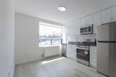 Located at 3101 Eglinton Ave E in Toronto's Scarborough neighbourhood, this two-bedroom, one-bathroom unit offers a clean, modern interior with a thoughtfully organized single-floor layout. Light wood laminate flooring runs throughout the space, complementing the crisp white walls and creating a bright, cohesive aesthetic.

The kitchen is a standout feature, equipped with stainless steel appliances including a refrigerator, electric range, and over-the-range microwave. White cabinetry extends to the ceiling for generous storage, and a dark countertop with an undermount sink adds contrast. A large window floods the kitchen with natural light and offers views of the surrounding area.

Both bedrooms are well-proportioned, with the primary bedroom offering a comfortable footprint. Each room features light-toned flooring, white walls, and windows that bring in natural light. Baseboard heating units are present in the bedrooms, ensuring year-round comfort. A dedicated closet provides practical storage.

The bathroom is finished with classic white subway tile surrounding a full soaker tub, delivering a clean and timeless look. The unit also includes a dedicated closet for additional storage needs. Overall, the space presents a modern, move-in-ready interior with functional design throughout.