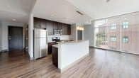Located at 411 River St in the heart of downtown Greenville, South Carolina, this modern single-floor residence offers a thoughtfully designed open layout with contemporary finishes throughout. Hardwood-style flooring flows seamlessly across every room, creating a cohesive and polished aesthetic.

The kitchen serves as a central hub of the space, featuring rich dark cabinetry, granite countertops, stainless steel appliances, and a curved peninsula island with pendant lighting overhead — ideal for both cooking and casual dining. The open layout connects directly to the living area, which is anchored by dramatic floor-to-ceiling windows that flood the room with natural light and offer expansive views of the surrounding downtown Greenville skyline and greenery. A ceiling fan adds both function and style to the bright living space, which also provides access to an outdoor balcony.

The bedrooms are well-sized, bright, and tranquil, with one featuring a dedicated walk-in closet with built-in shelving. The bathrooms are finished with granite-topped dark vanities, large mirrors, and tiled shower and tub surrounds. A utility closet houses a stacked front-load washer and dryer alongside additional shelving, providing convenient in-unit laundry. The overall ambiance is clean, contemporary, and inviting.
