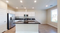 This two-story home presents a clean, modern design with a cohesive aesthetic carried throughout its living spaces. The kitchen serves as a central highlight, featuring crisp white cabinetry extending to the ceiling, dark granite countertops, and a full suite of stainless steel appliances including a French door refrigerator, range, built-in microwave, and dishwasher. A large island with a matching granite surface and undermount sink adds both functional workspace and a natural gathering point. Light wood-style flooring runs throughout the main living areas, complementing the neutral wall tones and recessed lighting overhead.

The bedrooms are carpeted in a warm beige tone and each include ceiling fans with integrated lighting. Multiple windows fitted with horizontal blinds allow for ample natural light while maintaining privacy. One bedroom features a generous walk-in closet with built-in shelving and dual hanging rods, providing substantial storage capacity.

The bathrooms continue the home's consistent design language, with white cabinetry, dark granite countertops, large mirrors, and wood-style flooring. A full bathroom includes a tub-shower combination with built-in shelving. A primary bathroom offers a wide dual-sink vanity and a window overlooking the exterior.