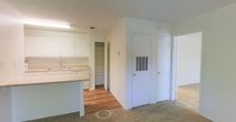 Located at 3500 Creighton Rd in Pensacola, Florida, this single-floor residence offers a practical and well-organized layout designed for comfortable everyday living. The kitchen is outfitted with white cabinetry that extends to the upper walls, providing generous storage space, along with light-toned countertops and a built-in sink. A kitchen island or peninsula adds additional workspace and helps define the transition between the kitchen and adjacent living areas. A dedicated walk-in pantry off the kitchen offers substantial shelving, making it ideal for organized storage of pantry goods and household essentials. The flooring throughout the space features a combination of warm hardwood in the kitchen and dining areas, transitioning to plush carpet in the living and hallway spaces, adding a sense of comfort underfoot. The walls are finished in a clean, neutral white throughout, contributing to a bright and open atmosphere. A hallway leads to additional rooms, with multiple doors suggesting private spaces such as bedrooms or utility closets. HVAC venting is integrated into the wall, reflecting a thoughtfully planned interior. Overall, the space presents a clean, move-in ready environment well-suited for functional residential living in the Pensacola area.