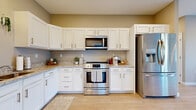 Located at 4252 Belden Greens Circle NW in Canton, Ohio, this single-floor residence offers a thoughtfully designed open-concept layout that maximizes its comfortable footprint. Light wood-style flooring flows continuously throughout the main living areas, creating a cohesive and bright atmosphere complemented by neutral warm-gray walls and recessed lighting.

The kitchen is a functional highlight, outfitted with white shaker-style cabinetry, granite countertops, and a full suite of stainless steel appliances including a range, built-in microwave, dishwasher, and refrigerator with water dispenser. A pendant light adds a refined touch above the sink area. The adjacent dining space accommodates a full dining set and connects seamlessly to the living room, which offers access to an in-unit laundry area.

The spacious primary bedroom features plush carpeting, a ceiling fan, and a large window that invites natural light. Two bathrooms are finished with white cabinetry, granite countertops, and wood-look tile flooring. A well-proportioned hallway connects the living areas to the private spaces, maintaining a logical and efficient flow throughout the unit.