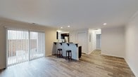 This single-floor residence at Cabin Creek offers a well-designed, open-concept layout that maximizes both functionality and comfort. The main living area is bathed in natural light streaming through large vertical-blind-dressed sliding doors, creating an airy and welcoming atmosphere. Light-toned hardwood flooring runs seamlessly throughout the space, lending a cohesive and contemporary feel.

The kitchen is positioned at the heart of the home, defined by a peninsula-style breakfast bar fitted with dark countertops and bar stool seating — ideal for casual dining or entertaining. Dark cabinetry contrasts cleanly against the light walls, and stainless steel appliances complete the modern aesthetic. Recessed lighting overhead ensures the kitchen remains bright and functional.

A hallway extending from the main living area leads to additional rooms, framed by crisp white doors and trim that maintain the home's clean, neutral palette. The corridor is well-lit, enhancing the sense of openness and flow through the residence.

Throughout the space, white walls and ceilings paired with recessed lighting create a consistently bright and polished environment. The overall design is understated and move-in ready, offering a practical yet stylish living experience at Cabin Creek.
