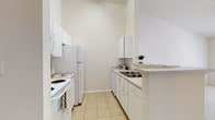 Located at 9525 US-78 Highway in Ladson, South Carolina, this single-floor residential unit offers a clean, light-filled layout designed for comfortable everyday living. The living area is finished with plush carpeting and features vaulted ceilings with a ceiling fan, creating an airy and open atmosphere. French doors lead out to a private balcony, allowing natural light to pour in and providing pleasant outdoor views. The kitchen is thoughtfully designed in a galley configuration, featuring white cabinetry, tile flooring, and a full suite of white appliances including a refrigerator, range, dishwasher, and microwave. A peninsula counter also offers a pass-through to the living area, enhancing the sense of connectivity throughout the unit. The bedroom is generously sized with soft carpeting and ample wall space, while the bathroom includes a single vanity with a wide mirror, tile flooring, and clean, neutral finishes throughout. Residents also have access to a well-appointed community fitness center, which features vaulted ceilings, a ceiling fan, wall-mounted television, rubber flooring, and an array of cardio and strength equipment alongside large windows that bring in natural light.