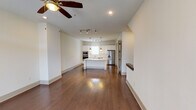 This well-designed two-floor residence offers a clean, modern aesthetic throughout, highlighted by rich hardwood flooring and a neutral color palette that creates a bright and welcoming atmosphere. The open-concept main living area flows seamlessly into the kitchen, which serves as the centerpiece of the home. The kitchen is outfitted with white shaker cabinetry, a large central island featuring a built-in cooktop and sink, quartz countertops, subway tile backsplash, and a full suite of stainless steel appliances including a double wall oven, microwave, dishwasher, and French door refrigerator. Pendant lighting and track lighting combine to illuminate the space beautifully. The living area is accented by a ceiling fan with light, recessed lighting, and a sliding glass door that invites natural light while providing access to an outdoor area. A convenient half bath is located on the main floor. Upstairs, carpeted bedrooms offer a comfortable retreat, each equipped with ceiling fans and ample closet space, including a generously sized walk-in closet with built-in shelving and hanging rods. The bathrooms are finished with clean tilework, glass-enclosed showers, white cabinetry, and modern chrome fixtures, delivering a polished and functional design throughout.