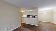 This single-floor residence offers a well-organized, open-concept layout designed for comfortable everyday living. The main living area is finished with rich, dark hardwood-style flooring and features a large sliding glass door dressed with vertical blinds, allowing natural light to fill the space and providing outdoor access. A pendant light fixture adds a finishing touch to the adjacent dining area.

The kitchen is positioned behind a half-wall pass-through counter, creating a connected yet defined cooking space. Inside, dark espresso cabinetry lines both walls, offering generous storage, while stone-look countertops provide ample prep space. Black appliances, including a refrigerator, electric range, and overhead microwave, complete the functional kitchen setup. The hardwood-style flooring continues seamlessly throughout.

The bedroom is a quiet, carpeted retreat with a window that invites natural light and provides a warm, restful ambiance. The textured ceilings carry consistently throughout the home, adding a classic residential character.

The bathroom is clean and straightforward, featuring a full-size soaking tub and shower combination with chrome fixtures. Throughout the home, neutral warm-toned walls, white trim, and consistent finishes create a cohesive and inviting atmosphere.