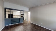 Located at 300 Jones Mill Rd in Statesboro, Georgia, this single-floor unit offers a practical and functional layout designed for comfortable everyday living. Throughout the main living areas, rich dark hardwood-style flooring creates a warm and cohesive aesthetic, complemented by neutral beige walls and textured ceilings.

The open living area is bright and welcoming, featuring a large window that allows natural light to fill the space. It connects seamlessly to the kitchen via a distinctive steel-framed pass-through partition with built-in shelving, adding a unique architectural detail to the layout.

The kitchen is well-equipped with white cabinetry, dark granite-style countertops, a double stainless steel sink, and black appliances including an electric range. Ample upper and lower cabinet storage makes the space highly functional.

The bedroom is carpeted for added comfort, features a ceiling fan with light fixture, and includes a window with natural light. A closet provides convenient storage directly off the room.

The bathroom is clean and straightforward, offering a single-sink vanity with white cabinetry, a toilet, and a shower-tub combination. Blue-gray wall-mounted cabinetry adds a touch of contrast and additional storage. The unit's layout is efficient, making it a practical living space in the Statesboro area.