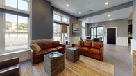 Located at 308 E Second St in Hummelstown, Pennsylvania, this single-floor communal space combines modern design with warm, inviting details to create a highly functional and visually appealing environment. The layout is open and generously proportioned, with polished concrete floors running throughout that lend a contemporary, industrial feel balanced by classic architectural touches.

The main lounge area is defined by rich cognac leather sofas and armchairs arranged around rustic wood coffee tables, all set atop warm-toned area rugs. Blue-gray painted walls paired with crisp white wainscoting create a refined two-tone aesthetic, while recessed lighting ensures the space is well-lit. Large windows allow abundant natural light to fill the room, offering views of the surrounding community.

A sitting alcove features a large decorative clock, framed wall art, and a flat-screen television, providing a more intimate gathering spot within the broader open floor plan. The kitchenette area is outfitted with dark espresso cabinetry, granite and stone countertops, a subway tile backsplash, and a distinctive reclaimed wood island — combining practicality with striking design. A glass-panel entry door connects this area directly to the exterior. Throughout, the space maintains a cohesive, upscale aesthetic that balances comfort and sophistication.