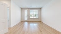 Located at 4700 Fossil Dr in Haltom City, TX, this well-appointed 2-bedroom, 3-bathroom residence offers a thoughtfully designed single-floor layout with a clean, contemporary aesthetic throughout. Light-toned wood flooring flows seamlessly across every room, complementing the crisp white walls and modern black hardware details that unify the space.

The kitchen is a standout feature, showcasing shaker-style cabinetry in a soft grey-white finish, a generous island with white quartz countertops, stainless steel appliances, and stylish pendant lighting — all oriented toward an open corridor leading to the main entrance. The adjacent living area receives abundant natural light through large windows fitted with horizontal blinds, and a glass-panel door provides direct access to an outdoor balcony.

Both bedrooms are well-proportioned and bright, each equipped with ceiling fans and windows offering neighborhood views. The primary bedroom benefits from its own dedicated bathroom and access to a closet. The bathrooms maintain the home's modern palette with white tile surrounds, quartz vanity tops, shaker-style cabinetry, and matte black fixtures. One bathroom includes a full soaking tub with tiled surround and convenient access to an adjacent closet. Two closets provide practical storage throughout the residence.