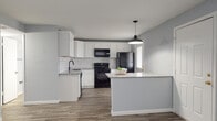 Ridge Manor is a thoughtfully updated single-story, 2-bedroom, 2-bathroom residence located in Sarasota, FL. The home features a cohesive design palette of soft gray walls and durable wood-look flooring that runs throughout every room, creating a warm and unified aesthetic.

The kitchen serves as a standout feature, showcasing white shaker cabinetry, granite countertops, and a classic white subway tile backsplash. Black appliances — including a range, over-the-range microwave, refrigerator, and dishwasher — provide a bold contrast to the bright cabinetry. A peninsula with pendant lighting offers additional counter space and separates the kitchen from the open living area, which benefits from natural light and a clean, open layout.

Both bedrooms are well-proportioned, each with natural light from windows fitted with vertical blinds and the same wood-look flooring found throughout the home. The bathrooms continue the design language established in the kitchen, with subway tile surrounding the bathtub/shower combination, granite countertops, matte black fixtures, and wood-look tile flooring. The exterior entry door in the kitchen area provides convenient access, completing this move-in-ready Sarasota residence.