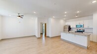 This single-story residence in Baton Rouge, Louisiana offers a clean, modern aesthetic throughout its well-organized floor plan, which includes four bedrooms, two full bathrooms, a living room, kitchen, dedicated laundry room, and two hallways. Light-toned hardwood-style flooring runs consistently throughout the home, contributing to a bright and cohesive interior.

The open-concept living and kitchen area serves as the central hub of the home. The kitchen is outfitted with white shaker-style cabinetry, granite countertops, a subway tile backsplash, stainless steel appliances including a refrigerator, electric range, and microwave, and a large island with an integrated sink. Recessed lighting and a ceiling fan illuminate the combined living space, which connects seamlessly to the hallways leading to the bedrooms.

Each bedroom features light flooring, ceiling fans, and windows fitted with horizontal blinds that allow natural light while maintaining privacy. Both bathrooms are finished with white cabinetry, granite vanity tops, and light flooring. One bathroom includes a tub-shower combination, while the second features a compact vanity setup. A dedicated laundry room provides added convenience within the home.