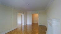 This single-floor space exudes timeless elegance through its thoughtfully preserved classical architectural details. The interior is immediately distinguished by its rich parquet hardwood flooring, laid in a herringbone-style pattern that adds warmth and visual depth to each room. Crisp white crown molding lines the upper perimeter of the walls, complementing the smooth, high ceilings and contributing to the space's refined character.

Doorways are a standout architectural feature, with a mix of graceful arched openings and traditional rectangular doorframes that create a sense of flow and connectivity between rooms. The walls are finished in a soft, neutral tone that enhances the brightness of the interior and provides a clean, welcoming ambiance.

Decorative chair rail molding and paneled wall detailing further elevate the classical aesthetic, lending a sense of craftsmanship and heritage to the space. The layout is open and well-proportioned, allowing natural light to move freely through the interconnected rooms. Overall, this space combines traditional architectural integrity with a versatile, light-filled interior — well-suited for those who appreciate classic design and quality craftsmanship.