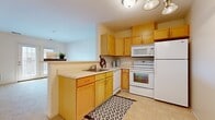 Located at 4400 E Lake Rd in Erie, PA, this single-floor, one-bedroom, one-bathroom unit offers a practical and well-organized layout. The kitchen is a functional highlight, featuring warm honey-toned wood cabinetry that extends to the upper and lower walls, light countertops, a built-in sink, and a full suite of white appliances including a range, microwave, dishwasher, and refrigerator. Light tile flooring and a patterned area rug add character to the space. The kitchen opens toward the living area, creating a connected, efficient flow throughout. The living room is carpeted and bathed in natural light, with a standout set of French doors that provide direct outdoor access and views of the surrounding exterior. The bedroom is a comfortably sized, carpeted retreat with a large window fitted with blinds, allowing for adjustable natural light. Neutral, warm-toned walls throughout the unit lend a calm and cohesive aesthetic. The bathroom is finished with tile flooring, a wood-toned vanity with a white countertop, a glass-enclosed shower, and thoughtfully included accessibility features such as a sturdy grab bar near the toilet. The overall layout is efficient and well-suited for comfortable single-occupant living.