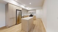 Located at 3250 Boulevard Henri-Bourassa Est in Montréal, this well-designed 4-bedroom, 1-bathroom unit offers a clean, contemporary aesthetic throughout its single floor. Light hardwood flooring runs consistently across all rooms, lending warmth and visual continuity to the space.

The open-concept kitchen is a standout feature, finished with light wood cabinetry, white upper cabinets, white quartz countertops, and stainless steel appliances including a full-size refrigerator and dishwasher. Recessed lighting illuminates the kitchen, which also benefits from an island or peninsula for additional workspace.

The living area is bright and airy, featuring large sliding glass doors that open to outdoor greenery, a wall-mounted mini-split air conditioning unit, and baseboard heating. The four bedrooms are finished in crisp white tones, each with light hardwood floors and baseboard heating. Several bedrooms feature windows with views of surrounding trees, and at least one includes a built-in sliding closet with panelled doors.

The bathroom is finished with light stone-effect floor tiles, a wood-toned vanity with storage, and a full-size soaker tub with a tiled shower surround. A hallway connects the rooms efficiently. The overall ambiance is clean, minimal, and move-in ready.