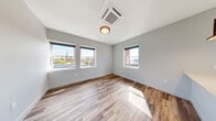 Located at 25 Lowell St in downtown Manchester, NH, this thoughtfully designed one-bedroom, one-bathroom unit offers a efficient and modern living experience across a single floor. Light-toned hardwood-style flooring flows consistently throughout, tying each space together with a clean, contemporary aesthetic.

The open-concept kitchen and living area serves as the heart of the unit. The kitchen is outfitted with white shaker cabinetry, stainless steel appliances, a full-size refrigerator, and a quartz waterfall island with an undermount sink and matte black faucet. Gold-toned geometric pendant lights add a striking design accent, while multiple windows frame views of the surrounding Manchester cityscape.

The bedroom is generously proportioned, featuring large windows that flood the room with natural light and offer views of the city, including a notable church steeple. A ceiling-mounted cassette HVAC unit provides year-round comfort. The room also includes a closet with sleek sliding panel doors.

The bathroom is finished in a clean, minimalist style with a stand-up shower featuring subway tile accents, a white vanity with black hardware, and coordinating fixtures throughout.

The entrance area includes a built-in wooden bench and coat hooks — a practical and stylish mudroom-style feature. In-unit laundry adds further convenience to this well-appointed urban residence.