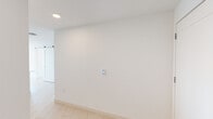 Located at 1818 Hollywood Blvd in Hollywood, Florida, this contemporary single-floor residence showcases a clean, modern design throughout. The open-concept living area is finished with light wood-look tile flooring and crisp white walls, creating a bright, airy atmosphere. Expansive floor-to-ceiling sliding glass doors flood the main living space with natural light while providing access to an outdoor area and sweeping views of the surrounding cityscape.

The kitchen is a standout feature, outfitted with a combination of high-gloss white upper cabinetry and warm wood-tone lower cabinetry, paired with a subtle tile backsplash. A large island with a marble-look countertop serves as a central gathering point, complemented by a full suite of stainless steel appliances including a French door refrigerator, electric range, built-in microwave, and dishwasher.

The bedrooms are well-proportioned, featuring recessed lighting, light tile flooring, and large windows that frame elevated city views. The primary bathroom offers a dual-sink vanity with a wood-tone base, vessel sinks, and a backlit mirror, alongside a glass-enclosed shower. A secondary bathroom includes a soaking tub with tiled surround and a single-sink floating vanity. Throughout the unit, recessed lighting and a neutral palette contribute to a refined, contemporary ambiance.