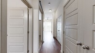 This efficiently designed 1-bedroom, 1-bathroom unit on a single floor makes smart use of its space across a living room, kitchen, bedroom, bathroom, and connecting hallways. The living area is bright and open, anchored by rich hardwood flooring and floor-to-ceiling vertical blinds covering a sliding glass door that invites natural light and outdoor views. A ceiling fan adds practical comfort to the space. The kitchen is well-appointed with dark espresso cabinetry, granite countertops, a decorative mosaic tile backsplash, and a full suite of stainless steel appliances including a range, dishwasher, and built-in microwave. The hallways connect the rooms efficiently, featuring a sliding barn door and panel-style doors that add a modern touch throughout. The bedroom is carpeted for warmth and comfort, offering a quiet retreat. The bathroom is finished with large-format tile flooring, a dark vanity with granite countertops, and a tiled tub-shower combination accented by a decorative mosaic border. Clean white walls and consistent finishes throughout give the unit a cohesive, contemporary aesthetic.