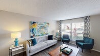 This single-floor residence offers a thoughtfully designed layout that balances comfort and functionality across its key living areas. The living room serves as the heart of the home, featuring wood-style flooring, a textured ceiling, and large windows dressed with patterned curtains that invite abundant natural light and outdoor views. The space accommodates a generous seating arrangement, making it ideal for both relaxing and entertaining.

Adjacent to the living room, a dedicated dining area features a sliding glass door that fills the space with natural light and provides outdoor access. A pendant light fixture anchors the dining nook, which comfortably fits a round table with modern transparent chairs.

The galley-style kitchen is efficiently organized with white cabinetry, dark countertops, wood-style flooring, and black appliances including a range and built-in microwave, offering ample storage and prep space.

The residence includes two bedrooms. The primary bedroom is notably spacious, featuring plush carpeting, multiple windows, and room for a full dresser and bedside furnishings. The secondary bedroom is cozily appointed with carpet flooring and a window overlooking the exterior.

Two full bathrooms each include a tub-shower combination, wood-style flooring, and vanity with dark countertops, providing practical and clean finishes throughout.