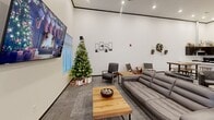 Located at 1908 Fox Rd in Rapid City, South Dakota, this single-floor community space offers a generously sized, open-concept layout designed for gathering and relaxation. The room features soaring ceilings with recessed lighting throughout, creating a bright and welcoming ambiance set against crisp white walls and neutral-toned carpet tiles.

The lounge area is thoughtfully arranged with multiple seating zones, including a curved sectional grouping with rounded accent chairs centered around a low cocktail table, as well as a cozy sofa arrangement with a wood coffee table and individual accent chairs. A wall-mounted flat-screen TV anchors the main lounge wall, complemented by decorative wall art. A pool table adds a recreational focal point to the open floor plan.

A high-top dining table with bar-height stools provides an additional social gathering area, offering a casual space for dining or conversation.

The kitchen area is a standout feature, boasting rich dark cabinetry with brushed nickel hardware, striking white quartz countertops with bold veining, and a large peninsula that doubles as a bar-height workspace. Stainless steel appliances — including a range with hood vent, refrigerator, and microwave — complete this fully functional kitchen. Natural light filters in through multiple windows fitted with horizontal blinds, enhancing the overall inviting atmosphere of the space.