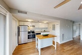 Located at 73 Charles St, Unit 400C in Providence, Rhode Island, this two-bedroom, one-floor unit offers a well-appointed layout with warm hardwood flooring throughout. The open living area is bright and spacious, with a ceiling fan overhead and large sliding glass doors that lead to a private balcony overlooking the surrounding brick buildings and urban greenery — a charming nod to Providence's historic character.

The kitchen is equipped with stainless steel appliances, including a full-size refrigerator, electric range, and dishwasher, complemented by white cabinetry, a under-cabinet range hood, and light countertops. A kitchen island with a butcher block top adds additional prep and dining space.

The primary bedroom is generously sized and features a vaulted ceiling, a ceiling fan, a distinctive arched window framing lush outdoor views, and a baseboard heating unit. Double closet doors provide ample storage. The second bedroom also features an arched window and good natural light, with a textured ceiling and hardwood floors.

Both bedrooms share the unit's consistent aesthetic of neutral tones, clean lines, and hardwood flooring. A wall-mounted air conditioning unit is present in one of the bedrooms. The overall ambiance is clean, functional, and comfortable, well-suited to urban residential living in Providence.