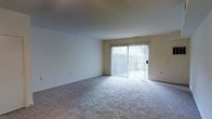 Located at 714 Riverside Drive in Salisbury, Maryland, this two-floor residence offers a straightforward and functional layout designed for comfortable living. The main living area is notably open and airy, featuring neutral-toned walls and wall-to-wall carpeting that contributes to a clean, understated aesthetic. A large sliding glass door serves as a prominent architectural feature, allowing generous natural light to fill the room while providing direct access to an outdoor area. Vertical blinds accompany the sliding door, offering both privacy and light control. The ceiling is smooth and standard in height, complementing the simplicity of the space. The open layout of the living area provides flexibility for a variety of furniture arrangements. The two-floor structure suggests additional living or sleeping spaces on the upper level, offering a degree of separation between common and private areas. Overall, the space presents a neutral, move-in-ready environment with practical features suited for everyday living in the Salisbury, Maryland area.