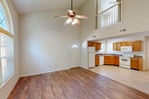 Located at 17 Kipling Way in Columbia, Missouri, this two-story, 3-bedroom, 2-bathroom home offers a well-designed layout spread across two floors. The main level makes an immediate impression with its soaring vaulted ceilings in the open-concept living area, where warm wood-style flooring extends throughout. A ceiling fan anchors the generous living space, which flows seamlessly into the kitchen. The kitchen features warm oak cabinetry, dark countertops, tile flooring, and a full suite of white appliances including a refrigerator, range, microwave, and dishwasher. An arched window on the main floor floods the space with natural light and frames views of the surrounding greenery. A white-railed staircase leads to the upper level, which overlooks the living area below, adding an open, connected feel. The bedrooms are comfortably sized, with ceiling fans, neutral carpet, and ample closet space, including sliding and panel-style closet doors. The primary bedroom features hardwood-style flooring and a large arched window. Both bathrooms are clean and functional, each equipped with a full tub-shower combination. A dedicated laundry area and utility room add everyday convenience to this practical and inviting home.