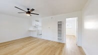 Located at 345 S Westlake Ave in Los Angeles, this 1-bedroom, 1-bathroom unit offers a clean, modern aesthetic throughout its single-floor layout. Light wood-style flooring runs continuously across every room, creating a cohesive and airy feel. Each room is equipped with a ceiling fan with integrated lighting, enhancing both comfort and illumination.

The open living area is bright and uncluttered, with white walls and a window dressed with blinds that allow natural light to filter in. The kitchen flows seamlessly from the living space and features white cabinetry, a microwave, and a peninsula countertop that doubles as a casual dining surface.

The bedroom is a comfortable, well-proportioned retreat featuring a mirrored sliding closet, a window with exterior views, and direct access to the bathroom. The bathroom is finished in a clean white palette, with marble-style tile flooring, a full tub-shower combo, a white vanity with under-cabinet storage, and a large mirror above the sink.

Throughout the unit, smart home entry keypads are visible, adding a modern, convenient touch. The overall design is minimalist and functional, making excellent use of the available space to deliver a practical yet polished living environment in the heart of Los Angeles.