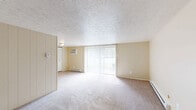 Located at 115 Timber Ridge Court in New Stanton, Pennsylvania, this single-floor, one-bedroom, one-bathroom residence offers a practical and comfortable layout with a well-defined use of space throughout. The living room is carpeted and bright, featuring large sliding glass doors fitted with vertical blinds that lead out to a private patio, allowing natural light to fill the room. A wall-mounted air conditioning unit and baseboard heating ensure year-round climate control. Adjacent to the living room, the kitchen is positioned for convenient access and includes hardwood-style flooring at the entryway transition. The bedroom is a comfortably sized, carpeted retreat featuring a window with horizontal blinds that brings in natural light and offers views of the surrounding greenery. The room includes a generous built-in closet with louvered bifold doors, providing ample storage. Baseboard heating is present in the bedroom as well, ensuring consistent warmth. In total, the residence includes three closets, offering excellent storage capacity throughout. Textured ceilings and neutral warm beige walls are consistent across the space, creating a cohesive and understated aesthetic. This single-story home provides a straightforward, functional floor plan well-suited for comfortable everyday living.