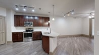 Located at 155 Birdsall St in Houston's 77007 zip code, this single-floor residence offers a well-appointed, open-concept layout designed for comfortable everyday living. The kitchen is a standout feature, showcasing rich dark wood cabinetry, granite countertops, and a full suite of stainless steel appliances including a range, microwave, and bottom-freezer refrigerator. A peninsula with an undermount sink and pendant lighting above creates a natural gathering point that connects the kitchen to the open living area. Wood-look plank flooring runs throughout the main living spaces, providing a clean, cohesive aesthetic accented by track lighting overhead. The bedroom is generously sized, finished with plush carpet, a ceiling fan, and direct access to both a spacious walk-in closet outfitted with wire shelving and a private en-suite bathroom. The bathroom features large-format tile flooring, a dual-sink vanity with granite countertops and dark wood cabinetry, a framed mirror, and a glass-enclosed shower. In-unit laundry hookups add everyday convenience. The neutral color palette and clean finishes throughout lend the space a move-in-ready, modern feel.