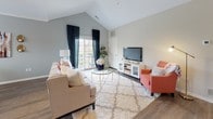 The Cherry floor plan in Canton, Michigan is a thoughtfully designed single-level residence offering two bedrooms and two full bathrooms. The layout flows naturally from the main living areas to the private sleeping quarters, maximizing functionality throughout.

The living room serves as the heart of the home, featuring striking vaulted ceilings that create an open, airy atmosphere. Large windows allow abundant natural light to fill the space, with access to an outdoor balcony enhancing the connection to the outdoors. Wood-style flooring adds warmth and continuity through the living and dining areas.

The kitchen is well-appointed with white shaker-style cabinetry, granite countertops, a subway tile backsplash, and a full suite of stainless steel appliances. A peninsula with an undermount sink provides additional workspace and casual seating.

The adjacent dining area is framed by a large window with outdoor views, creating a bright and inviting setting for meals.

Both bedrooms offer comfortable proportions with plush carpeting. The primary bedroom connects conveniently to the kitchen area. The two bathrooms are finished with granite-topped vanities and white cabinetry, with one featuring a walk-in shower and the other a tub-shower combination.
