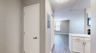 Located at 722 Walnut St in Kansas City, MO, this one-bedroom, one-bathroom residence offers a smartly designed layout that makes efficient use of its space. Light-toned luxury vinyl plank flooring runs consistently throughout, complementing the neutral gray and beige wall palette found in every room.

The living area is bright and open, with large windows fitted with horizontal blinds that welcome abundant natural light. The kitchen is a standout feature, boasting crisp white shaker cabinetry, a marble-look tile backsplash, white countertops, and black appliances including a refrigerator, range, and dishwasher — a clean, contemporary combination.

A connecting hallway leads to the generously sized bedroom, which offers two closets providing ample storage space, along with a window that brings in additional natural light. Further rooms along the hallway maintain the same clean, modern aesthetic with neutral tones and consistent flooring.

The bathroom includes a full tub and shower combo with white tile surround and brushed bronze fixtures, adding a warm, classic touch. Throughout the residence, the design is cohesive and move-in ready, with a clean, minimalist aesthetic well-suited for urban living in downtown Kansas City.