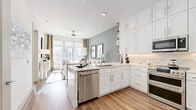 This well-appointed one-bedroom, one-bathroom residence in Austin, TX offers a thoughtfully designed open-concept layout that maximizes every square foot. The combined kitchen and living area serves as the heart of the home, featuring rich wood-style flooring, crisp white shaker cabinetry extending to the ceiling, quartz countertops, and a peninsula island ideal for dining or entertaining. Stainless steel appliances — including a gas range, built-in microwave, dishwasher, and French door refrigerator — complete the chef-friendly kitchen. The living area is bathed in natural light from expansive floor-to-ceiling windows, offering urban views of the surrounding Austin skyline and a ceiling fan overhead. The bedroom is a serene retreat with soft carpet, a muted sage accent wall, large windows with drape panels, and access to a dedicated closet with built-in shelving. The bathroom features a floating white vanity with a quartz countertop, a glass-enclosed soaking tub, and warm wood-tone flooring. A dedicated closet with built-in organization adds practical storage. The overall ambiance is clean, contemporary, and light-filled — ideal for modern urban living in the heart of Austin.