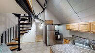 Located at 2633 16th St NW in Washington, DC, this distinctive two-floor space offers a compelling blend of character and functionality. The layout spans two levels connected by both a spiral staircase and a straight staircase with wooden railings, giving the space a dynamic, multi-dimensional feel.

The kitchen is a standout area, situated beneath soaring angled ceilings with exposed black structural beams that lend an industrial-chic aesthetic. Light wood cabinetry pairs with granite countertops and stainless steel appliances, including a refrigerator and electric range. Tile flooring grounds the space practically while complementing the raw, textured ceiling above.

Living and bedroom areas feature warm hardwood floors throughout, with clean white walls that maximize brightness. One room showcases a gracefully curved wall, adding an architectural flourish rarely seen, topped with a ceiling fan for comfort. Open arched doorways connect the rooms, creating a natural flow between spaces.

The bathrooms are finished with granite-topped vanities and tile flooring. One full bathroom includes a tub-shower combination, while a second bathroom offers a standalone walk-in shower. Both are clean and functional in design.

This space delivers a memorable combination of historic architectural character and practical modern updates, ideally situated in one of Washington, DC's most sought-after neighborhoods.