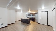 This single-floor unit is designed with an open-concept layout that seamlessly connects the living area and kitchen, creating a spacious and functional environment. Light wood-tone luxury vinyl plank flooring runs throughout the main living spaces, complementing the clean white walls and textured ceilings illuminated by flush-mount ceiling fixtures.

The kitchen is well-appointed with dark espresso cabinetry, gray countertops, and a full suite of stainless steel appliances, including a range, microwave, and refrigerator. A central island with an integrated sink adds additional prep space and casual dining potential. A dedicated laundry area with washer and dryer hookups is conveniently positioned adjacent to the kitchen.

The two bedrooms are carpeted and each include a window that brings in natural light, with one bedroom featuring a sliding closet. Two bathrooms mirror the kitchen's design aesthetic, offering dark cabinetry, gray countertops, undermount sinks, and wood-tone flooring. The primary bathroom includes a stand-up shower with glass sliding doors, while the secondary bathroom provides a compact, efficient layout. Overall, the unit presents a cohesive, modern aesthetic throughout.