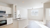 This well-designed 2-bedroom, 3-bathroom residence offers a clean, modern aesthetic with an efficient single-floor layout. The open-concept kitchen and living area serves as the heart of the home, featuring a central island with granite countertops and a built-in sink, crisp white cabinetry, a subway tile backsplash, and stainless steel appliances including a side-by-side refrigerator. Built-in shelving adds functional character to the kitchen wall. Light wood-look flooring flows seamlessly throughout the entire residence, contributing to a cohesive and airy feel.

The living room benefits from a large window that floods the space with natural light and a ceiling fan overhead. Both bedrooms continue the bright, neutral palette with large windows, ceiling fans, and generous natural light. The primary bedroom is comfortably sized and is complemented by two well-appointed closets, including a walk-in closet outfitted with wire shelving for ample storage.

The bathrooms are thoughtfully finished, with at least one featuring a soaking tub framed by full-height marble-look tile surround. Throughout the residence, the consistent use of neutral tones, light flooring, and modern fixtures creates a clean, contemporary living environment.