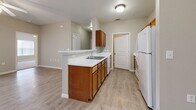 Located at 6200 Loyola Ln in Austin, TX, this single-story, 2-bedroom, 3-bathroom home offers a practical and comfortable layout across a well-utilized floor plan. The living area features light wood-look flooring, a ceiling fan, and a glass-paneled door alongside a window that brings in natural light, creating a welcoming, open feel.

The kitchen is a functional highlight, featuring warm honey-toned wood cabinetry, white countertops, a peninsula with a sink that opens toward the living area, and white appliances including a refrigerator and oven. Light flooring throughout the kitchen and common areas creates a cohesive, clean aesthetic. A dedicated utility room is accessible directly from the kitchen.

Both bedrooms are carpeted and feature ceiling fans. The primary bedroom is generously sized, offering a double-door closet and direct access to an en-suite bathroom. The second bedroom includes a walk-in closet. The bathrooms are consistent in design, each featuring warm wood vanity cabinetry, white countertops, and light wood-look tile flooring. One bathroom includes a full tub-shower combination with clean white surrounds.

Neutral gray-beige wall tones throughout the home provide a versatile backdrop, and white trim and panel doors add a crisp, finished look to every room.
