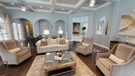 This single-story clubhouse is a beautifully designed community gathering space that combines classic architectural elegance with upscale amenities. The main lounge area immediately impresses with soaring coffered ceilings, soft blue-gray walls, and rich dark hardwood flooring that flows throughout. Graceful arched doorways and alcoves with wainscoting details create a refined visual rhythm, connecting the various spaces seamlessly.

The primary seating area is furnished with plush neutral sofas and wingback chairs arranged around a gold-framed glass coffee table, creating an inviting setting for relaxed socializing. Adjacent to this is a spacious great room featuring a stately white fireplace, a wall-mounted television, and arched windows dressed with elegant patterned drapes that bathe the room in natural light.

The entertainment room serves as a standout feature, offering a full-size billiards table as its centerpiece, flanked by a bar-height counter with seating, multiple flat-screen televisions, and rows of clerestory arched windows that add dramatic height and light. A cozy bistro-style nook with textured dark walls provides an intimate retreat within this space.

The clubhouse kitchen is equipped with a professional-grade stainless steel range, a classic white subway tile backsplash, and crisp white cabinetry with quartz countertops — fully functional for events and gatherings.