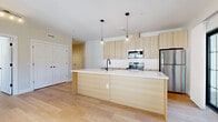 This thoughtfully designed one-bedroom, one-bathroom residence in Brookfield, CT offers a bright, modern living experience across a single floor. Light-toned hardwood flooring flows seamlessly throughout, unifying the open-concept layout and creating a warm, cohesive aesthetic.

The heart of the home is a stunning kitchen and living area, anchored by a generous center island with a quartz countertop, black matte fixtures, and a built-in sink with dishwasher. Light wood cabinetry extends to the ceiling, complemented by a classic white subway tile backsplash and stainless steel appliances, including a range, microwave, and refrigerator. Globe pendant lights add a stylish finishing touch overhead. The adjoining living and dining area is bathed in natural light through multiple black-framed windows.

The bedroom is a serene retreat, featuring large windows that invite abundant daylight and offer views of the surrounding neighborhood. Track lighting and clean, neutral walls complete the space. Two closets provide ample storage.

The bathroom is finished with light tile flooring, wood-toned vanity cabinetry, and crisp white Shaker-style doors. A dedicated laundry area and hallway round out this well-appointed, move-in-ready residence.