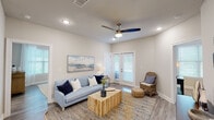 This well-appointed 2-bedroom, 2-bathroom residence in Hammond, Louisiana, is designed with a thoughtful single-floor open-concept layout that promotes seamless flow between living spaces. The kitchen serves as a central hub, featuring rich dark cabinetry, granite countertops, a subway tile backsplash, and a full suite of stainless steel appliances including a range, microwave, and refrigerator. A generous kitchen island with seating for multiple guests extends toward the dining area, making it ideal for both everyday meals and entertaining.

The living room is bright and welcoming, with recessed lighting, a ceiling fan, and French doors that invite natural light and outdoor access. Light wood-look flooring extends throughout the unit, creating a clean and cohesive aesthetic.

Both bedrooms are comfortably sized, each with ceiling fans, natural light from well-positioned windows, and direct access to their respective bathrooms. The bathrooms mirror the kitchen's design language with granite-topped dark vanities, providing a consistent, polished finish throughout the unit.

A dedicated laundry room houses full-size washer and dryer units alongside upper cabinetry for additional storage. The overall design balances modern finishes with functional living, making this a practical and attractive residence in Hammond, LA.