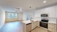 Located at 415 Stump Rd in Montgomeryville, PA, this thoughtfully designed one-bedroom, two-bathroom residence offers a clean, contemporary aesthetic throughout its well-appointed single floor. The open-concept kitchen and living area serves as the heart of the home, showcasing light wood-toned lower cabinetry paired with crisp white upper cabinets that extend to the ceiling for generous storage. A peninsula with a white quartz countertop and matte black single-basin sink anchors the kitchen, complemented by a full suite of stainless steel appliances including a refrigerator, electric range, microwave, and dishwasher. A sleek linear pendant light and adjustable track lighting illuminate the space, while large windows invite abundant natural light into the adjoining living area. The bedroom is a comfortable retreat finished with plush carpet, large windows with exterior views, and access to a spacious walk-in closet equipped with wire shelving systems. Two full bathrooms serve the residence, one featuring a glass-enclosed walk-in shower with matte black hardware and wood-look tile flooring. Throughout the main living areas, light-toned wood plank flooring ties the modern design together, creating a bright, cohesive, and move-in-ready space.