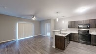 This single-floor residence at 2230 S Ellis Rd in Sioux Falls, South Dakota, offers a thoughtfully designed open-concept layout with modern finishes throughout. The living area is spacious and inviting, featuring warm hardwood-style flooring, neutral gray walls, and a ceiling fan that enhances comfort. Large vertical-blind-covered sliding doors allow natural light to flow generously into the space, creating a bright and airy atmosphere.

The kitchen is a standout feature, showcasing rich dark-toned cabinetry paired with striking marble-patterned countertops that extend across ample prep surfaces. A peninsula with a built-in sink adds functionality and defines the transition between kitchen and living areas. Pendant lighting above the peninsula and black Whirlpool appliances—including a range, microwave, dishwasher, and refrigerator—complete the polished look.

The bedroom offers plush carpeting, a window with natural light, and a calm, neutral color palette. The bathroom is well-appointed with a dark vanity cabinet, a lighted mirror, a full soaking tub, and hardwood-style flooring that ties the space together cohesively.

A dedicated laundry area houses a full-size Whirlpool washer and dryer set with overhead shelving, providing practical convenience. Every detail of this residence reflects a clean, contemporary design aesthetic ideal for modern living.