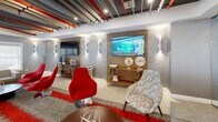 The Somerville Parc Work Area in Somerville, NJ, is a thoughtfully designed, single-floor workspace that blends modern aesthetics with practical functionality. The space is immediately distinguished by its striking ceiling treatment — a dynamic arrangement of layered beams and acoustic panels in charcoal, gray, and bold red, which adds depth and visual interest throughout the area.

The open layout is anchored by multiple seating zones furnished with vibrant red swivel chairs, neutral-toned sofas, and patterned accent chairs, all arranged around low round tables to encourage collaboration and conversation. A plush area rug with red accents grounds the central lounge, tying the color palette together cohesively.

Glass partitions with barn-style sliding hardware define a semi-private inner area, offering a sense of separation while maintaining visual openness across the floor. This glassed enclosure features a reception-style counter and wall-mounted display screen, suitable for check-ins or focused work sessions.

Along the perimeter, a wood-paneled media wall showcases a large flat-screen television flanked by sculptural wall sconces, creating a polished media lounge atmosphere. Natural light filters in through large windows, complemented by recessed and track lighting that ensures the space remains bright and welcoming at all hours. The overall ambiance is energetic yet refined, ideal for productive work and community engagement.