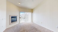 This well-appointed single-floor residence offers a thoughtfully designed layout that balances comfort and functionality. The living room serves as the centerpiece of the home, boasting vaulted ceilings, a ceiling fan, and a tile-surround fireplace that anchors the space with warmth and character. A sliding glass door with vertical blinds opens to an outdoor balcony, flooding the room with natural light and providing pleasant exterior views. An elegant arched passage connects the living area to additional rooms, adding an architectural touch that enhances the open feel of the interior.

The dining area flows seamlessly into the kitchen, which is equipped with light wood cabinetry, a white appliance suite including a refrigerator, electric range, and dishwasher, and a peninsula breakfast bar with neutral countertops. Wood-look flooring in the kitchen and dining space contrasts beautifully with the plush carpeting found throughout the living and bedroom areas.

The bedroom is generously proportioned, featuring its own sliding glass door to the balcony, allowing for ample natural light and outdoor access. The full bathroom is clean and functional, offering a tub-shower combination with tile surround, a light wood vanity with a wide mirror, built-in open shelving, and wood-look flooring that ties the space together cohesively.