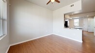 This two-story home in Tulsa, Oklahoma offers a thoughtfully designed layout spread across two floors. The main level features a welcoming entryway with a wood-railed staircase and natural light from a sidelight window. The open living room connects seamlessly to the kitchen via a pass-through window, and is appointed with warm wood-look flooring and a ceiling fan. The kitchen is well-equipped with rich dark cabinetry, a subway tile backsplash, light countertops, a center island, and full black appliance suite including a refrigerator, electric range, and over-the-range microwave. A full bathroom with a soaking tub, wood-look flooring, and brushed nickel hardware completes the main level. Upstairs, the primary bedroom offers generous proportions, dual closets, and a large window that fills the room with natural light. A second bedroom and an additional full bathroom with a vanity featuring a wide mirror and dark cabinetry are also found on the upper level. A hallway connects the upper-floor rooms, along with dedicated closet storage and an in-unit laundry area. Throughout the home, consistent wood-look flooring, neutral wall tones, and six-panel white doors create a clean, cohesive aesthetic.
