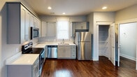 Located at 751 Riverfront Parkway in Chattanooga, Tennessee, this well-appointed multi-story property spans three floors and showcases a thoughtful blend of modern finishes and functional design. Rich, dark hardwood flooring flows throughout the main living areas, complemented by neutral gray tones on the walls that create a clean and contemporary atmosphere.

The main floor features a bright, open living area with recessed lighting and a welcoming entryway. The kitchen is equipped with stainless steel appliances, including a range, microwave, dishwasher, and refrigerator, set against crisp white quartz countertops and shaker-style cabinetry. A convenient half bath is also found on this level.

Upstairs, bedrooms offer plush carpeting and generous natural light through large, trimmed windows. A standout upper-level bedroom features soaring vaulted ceilings with a ceiling fan, lending an airy, expansive feel. The primary bathroom is a highlight, boasting a glass-enclosed walk-in shower with subway tile, a soaking tub, a dual-vanity with blue cabinetry, and a walk-in closet. A secondary full bathroom provides a tub-shower combo with tile flooring and a sleek vanity.

The staircase, with its dark wood treads and classic white risers, adds architectural elegance connecting all three levels of this well-designed Chattanooga property.
